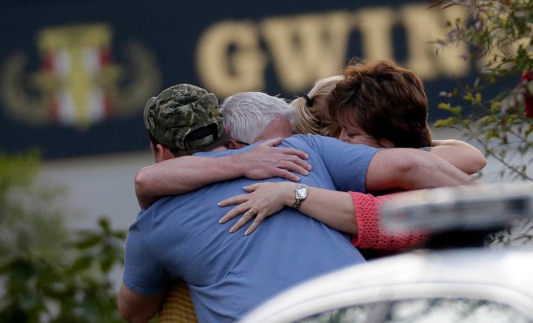 A group of people huddle together after an explosion and gunshots were heard near the scene where a man was holding four firefighters hostage Wednesday, April 10, 2013 in Suwanee, Ga. A police spokesman said the suspect was dead and none of the hostages suffered serious injuries. (AP Photo/John Bazemore)