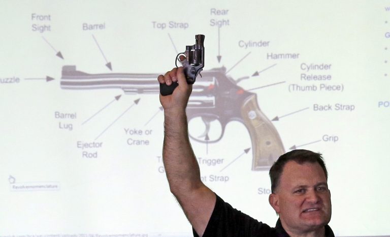 FILE - In this Dec. 27, 2012, file photo, Clark Aposhian, president of Utah Shooting Sport Council, holds a pistol during concealed weapons training for 200 Utah teachers, in West Valley City, Utah, with a diagram of gun parts projected behind him. Utah's top gun lobbyist will once again be able to access his arsenal after resolving a criminal case against him. On Monday, June 23, 2014, Aposhian pleaded no contest to a disorderly conduct infraction stemming from honking a horn, and was ordered to pay a $320 fine. His lawyer says Aposhian feels 
