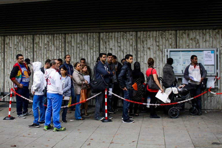 Refugees line up to apply for asylum at the reception center in Berlin, Germany, Tuesday, Sept. 30, 2014. A top government official says all personnel working for security companies at asylum centers will have to undergo a police background screening before working with refugees. The interior minister of North Rhine-Westphalia Ralf Jaeger on Tuesday announced the new measure after allegations surfaced over the weekend that private security guards had repeatedly abused refugees at an asylum center in Burbach in western Germany. (AP Photo/Markus Schreiber)