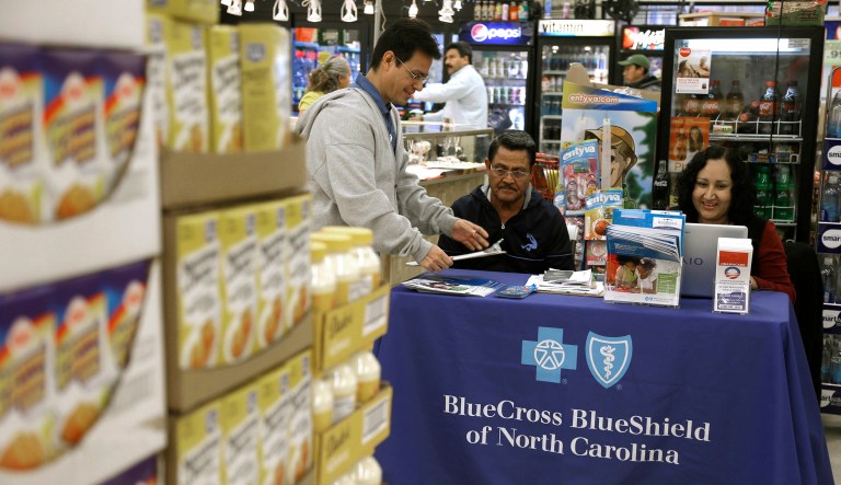 FILE - In this Saturday, Nov. 22, 2014, file photo, Blue Bridge Benefits LLC agent Patricia Sarabia, right, and Adolfo Briceno, left, with Spanish Speaking LLC, help a potential customer with Blue Cross Blue Shield at a kiosk promoting health insurance under the federal Affordable Care Act, at Compare Foods in Winston-Salem, N.C. People shopping for insurance through the Affordable Care Act in yet more regions will be facing higher prices and fewer choices in the coming year as insurance companies lay out their early plans for 2018. Blue Cross and Blue Shield of North Carolina said Thursday, May 25, 2017, it wants a 23 percent price hike in 2018 because it doesn't expect crucial payments from the federal government to continue. (AP Photo/Gerry Broome, File)