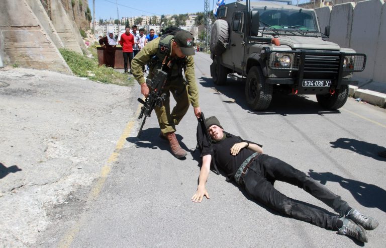An Israeli soldier detains a foreign protester during a demonstration calling for no more Israeli settlements in Hebron in front of a disputed building in the West Bank city of Hebron near the Israeli settlement of Kiryat Arba, Friday, April 11, 2014. Israeli settlers and Palestinians both claim ownership of the property. (AP Photo/Nasser Shiyoukhi)