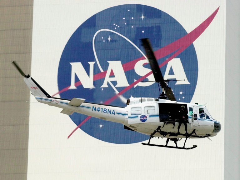 A NASA security helicopter flies by the NASA logo at the Kennedy Space Center in Cape Canaveral, Fla.(AP/Paul Kizzle)