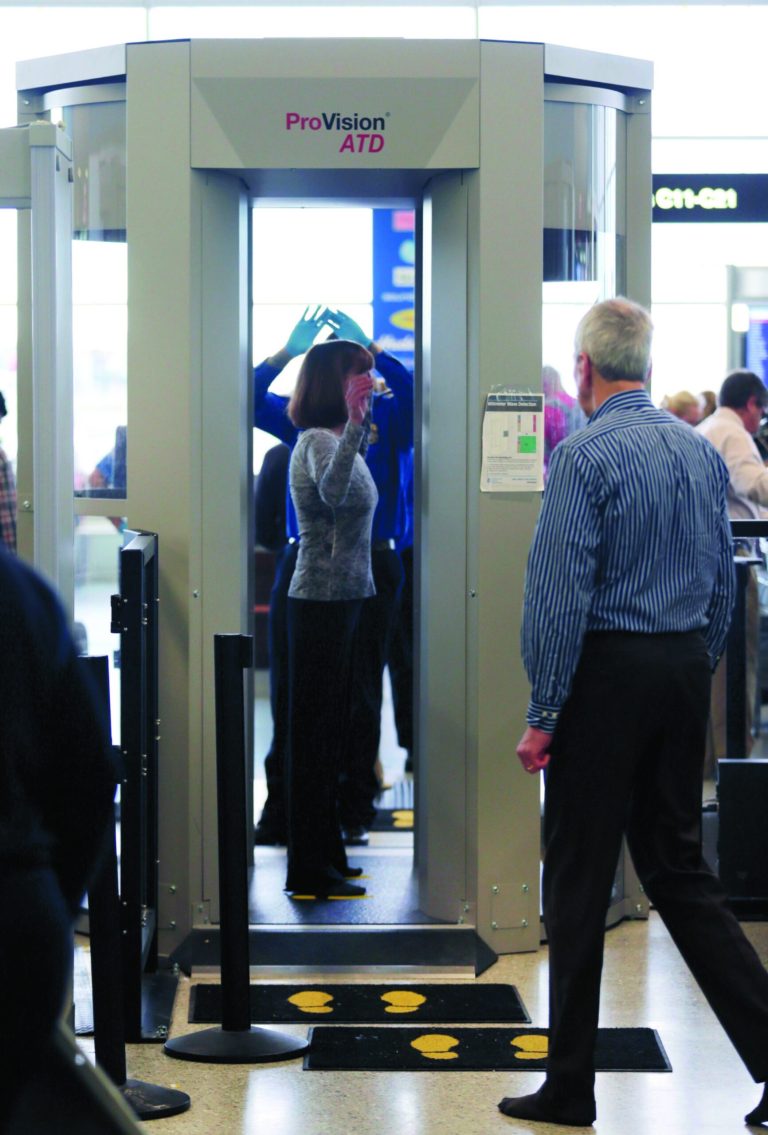 In this Wednesday, Oct. 24, 2012 photo, passengers are scanned at a Terminal C security checkpoint at Logan Airport in Boston using a millimeter wave body scanner, which produces a cartoon-like outline rather than naked images of passengers produced by a similar machine using X-rays. The Transportation Security Administration is deploying more of the millimeter waveÃmachines at seven major U.S. airportsÃwhere the agency is removing all of the full-body X-ray scanners that have been criticized by privacy advocates. (AP Photo/Charles Krupa)