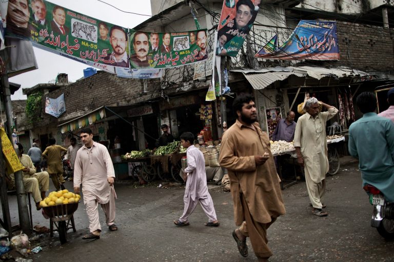Pakistanis walk under election banners showing former prime minister, leader of Pakistan Muslim League-N, Nawaz Sharif, and other members of his party, in Rawalpindi, Pakistan, Sunday, May 12, 2013. Pakistan's former prime minister Nawaz Sharif looked set Sunday to return to power for a third term, with an overwhelming election tally that just weeks ago seemed out of reach for a man who had been ousted by a coup and was exiled abroad before clawing his way back as an opposition leader. (AP Photo/Muhammed Muheisen)