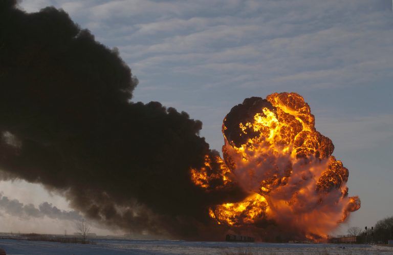 FILE - In this Dec. 30, 2013 file photo, a fireball goes up at the site of an oil train derailment in Casselton, N.D.  Railroads that haul volatile crude shipments have reached an agreement with U.S. transportation officials to adopt wide-ranging voluntary safety measures after a string of explosive and deadly accidents. A copy of the agreement between the U.S. Transportation Department and the Association of American Railroads obtained Friday, Feb. 21, 2014 by The Associated Press calls for railroads to slow down oil trains through major cities, increase track inspections and bolster emergency response planning along routes that see trains that can haul up to three million gallons of oil each. (AP Photo/Bruce Crummy, File)