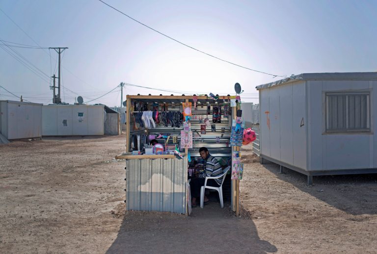 In Thursday April 17, 2014 photo, Syrian refugee Abu Mohammed sits in a shop he has set up to sell women's accessories to boost his non-existent income at Zaatari refugee camp, near the Syrian border in Jordan. It was hard enough for Abu Mohammed to flee his hometown of Daraa in southern Syria because of the raging fighting. He now has to survive on basics in this sprawling refugee camp in Jordan, and pay rent to a fellow Syrian strongman for the use of a small plot of land to set up a shop.(AP Photo/Khalil Hamra)