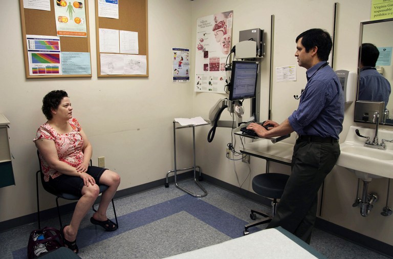 Amanda Thornton of Aloha, Ore., speaks with primary care doctor John Guerreiro at a clinic run by the Virginia Garcia Memorial Health Center in Beaverton, Ore. The center comprised of nine clinics in northwestern Oregon, serveing 36,000 patients in Washington and Yamhill has been overwhelmed under the Affordable Health Care Act's Medicaid expansion. (AP Photo/Gosia Wozniacka)
