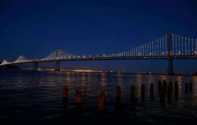 In this Wednesday, Feb. 20, 2013, photo,lights are turned on along the western half of the San Francisco-Oakland Bay Bridge on Pier 14 in San Francisco. The San Francisco-Oakland Bay Bridge has been turned into the latest, and by far the biggest, backdrop for New York artist Leo Villareal, who has individually programmed 25,000 white lights spaced a foot apart on 300 of the span's vertical cables to create what is being billed as the world's largest illuminated sculpture. (AP Photo/Jeff Chiu)