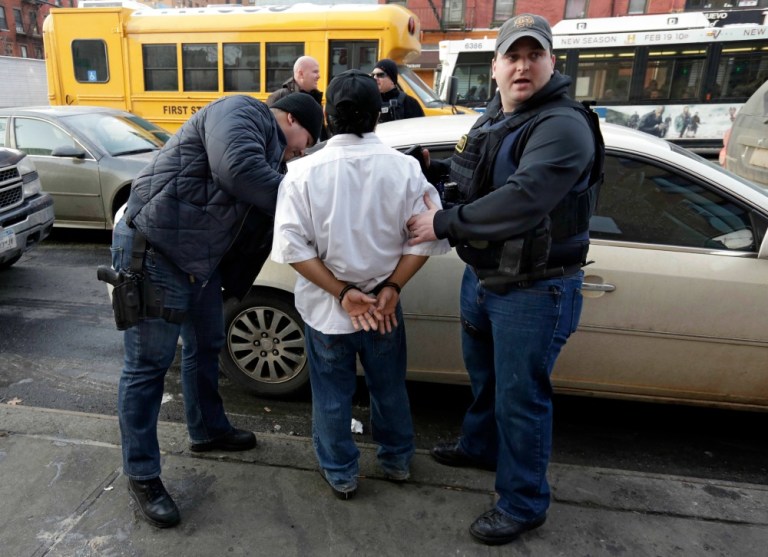 In this March 3, 2015 photo, Immigration and Customs Enforcement officers make an arrest in New York, during a series of early-morning raids. Immigrant and Customs Enforcement say an increasing number of cities and counties across the United States are limiting cooperation with the agency. (AP Photo/Richard Drew)
