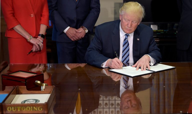 President Donald Trump signs a memorandum on Orderly Liquidation Authority, Friday, April 21, 2017, at the Treasury Department in Washington. Trump signed an executive order to review tax regulations set last year by his predecessor, as well as two memos to potentially reconsider major elements of the 2010 Dodd-Frank financial reforms passed in the wake of the Great Recession. (AP Photo/Susan Walsh)
