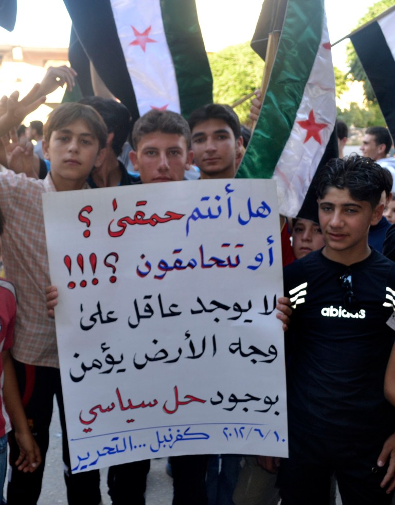  This citizen journalism image provided by Shaam News Network SNN, taken on Sunday, June 10, 2012 purports to show Syrians holding a poster in Arabic that reads, 