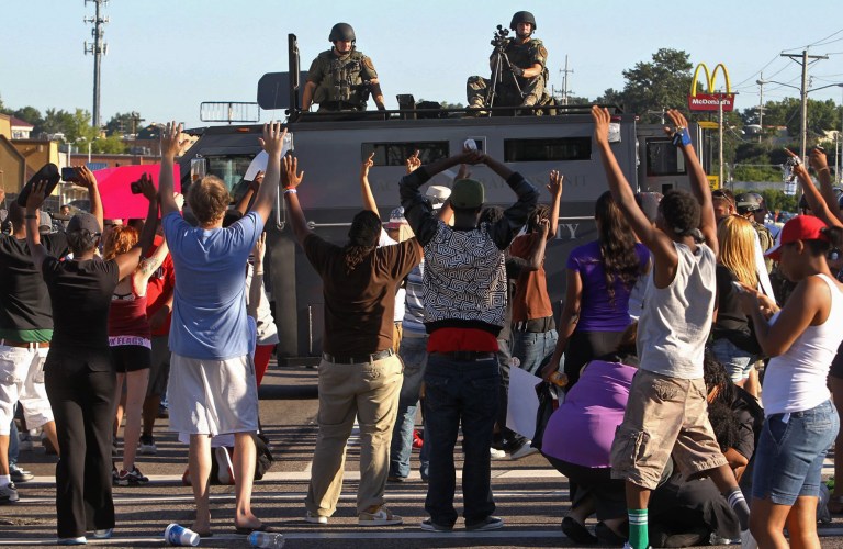 Protesters raise their hands in front of police atop an armored vehicle in Ferguson, Mo. on Wednesday, Aug. 13, 2014. On Saturday, Aug. 9, 2014, a white police officer fatally shot Michael Brown, an unarmed black teenager, in the St. Louis suburb. (AP Photo/St. Louis Post-Dispatch, J.B. Forbes)