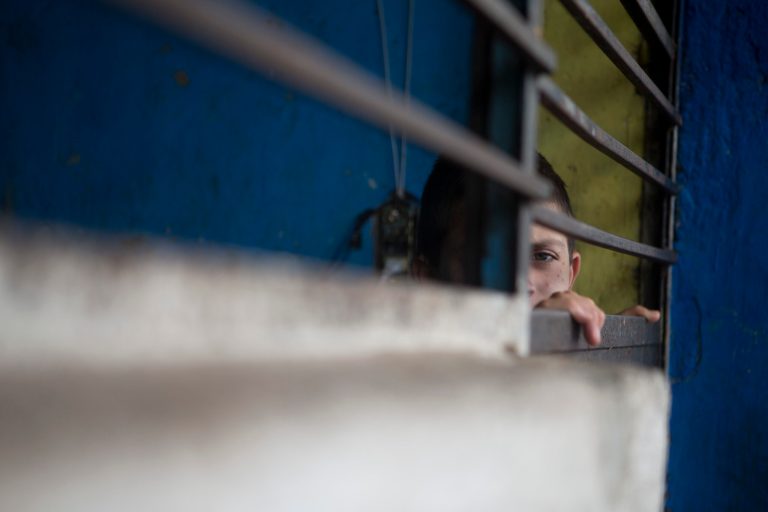 In thus Thursday, July 17, 2014 photo, a boy peers out through the door of a cell-like room inside The Great Family group home in Zamora, Mexico. After a police raid on the refuse-strewn group home, residents of the shelter told authorities that some employees beat residents, fed them rotting food or locked them in a tiny 