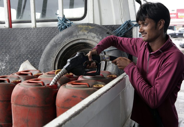   In this Saturday, Dec. 1, 2012 photo, a man fills gasoline in plastic containers at a gas station in Doha, Qatar. The host of the current U.N. climate talks, Qatar, is among dozens of nations that keep gas prices low through subsidies that exceeded $500 billion globally last year. (AP Photo/Osama Faisal)  