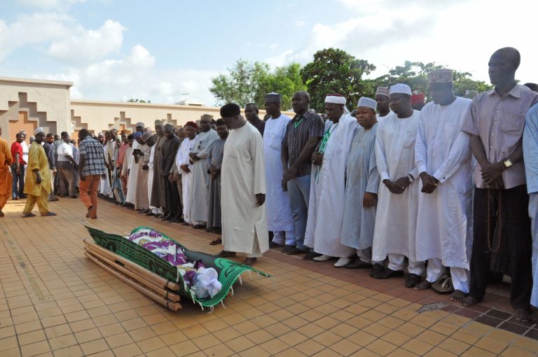 People stand over the remains  blast victim Suleiman Bisalla , during his funeral,  after the explosion in Abuja, Nigeria, Thursday, June 26, 2014. The National Hospital spokesman says a victim wounded in the bomb blast at a mall in Nigeria's capital died overnight. The government says soldiers shot and killed one suspect as he tried to escape, and police detained a second suspect. (AP Photo/Olugbemiga Babatunde)