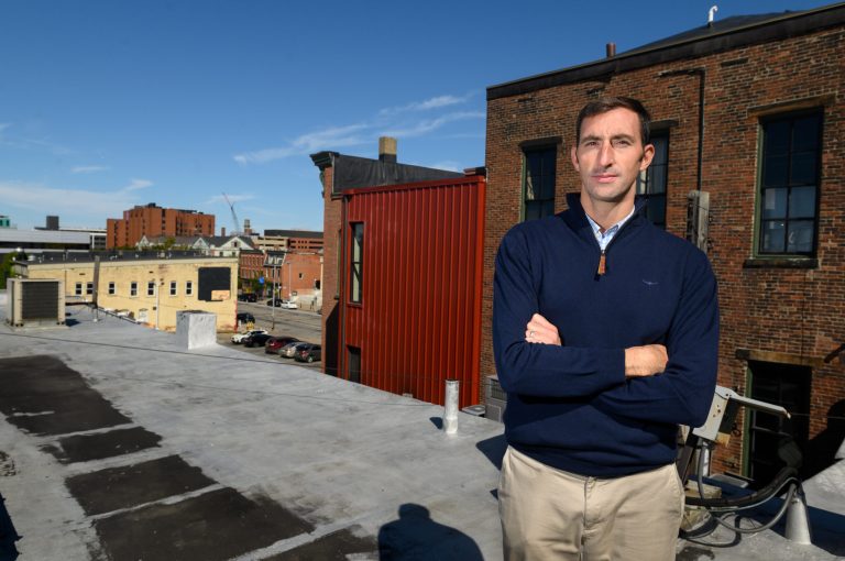 John Persinger, CEO of the Erie Downtown Development Corp., stands on the rooftop of one of the buildings that the corporation purchased along State Street and North Park Row in Erie, Pa. 