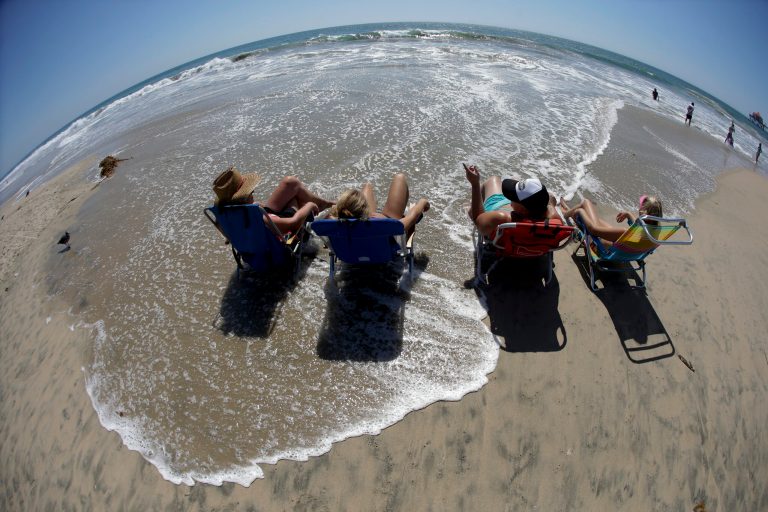In this photo taken with a fisheye lens, beach goers cool off during the Southern California heat wave, Monday, Sept. 15, 2014, in Huntington Beach, Calif. Southern California is roasting in triple-digit temperatures and forecasters say the heat wave will continue at least another day. (AP Photo/Chris Carlson)
