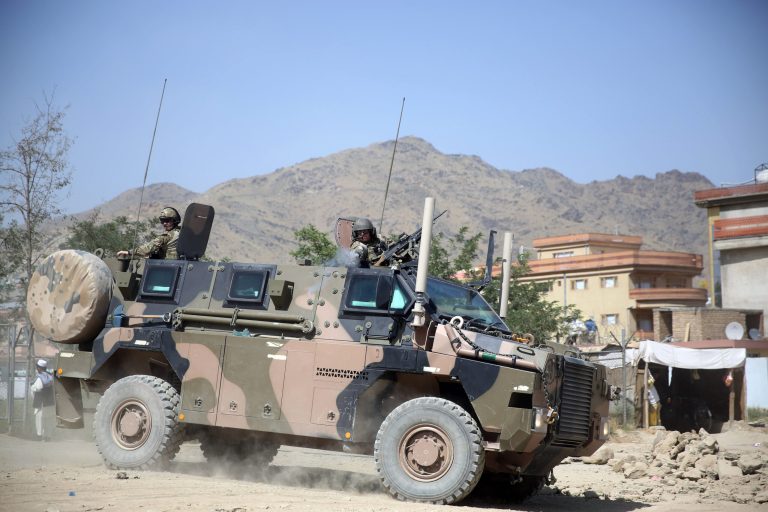 A NATO soldier, right, opens fire in an apparent warning shot in the vicinity of journalists near the main gate of Camp Qargha, west of capital Kabul, Afghanistan, Tuesday, Aug. 5, 2014. (AP Photo/Massoud Hossaini)