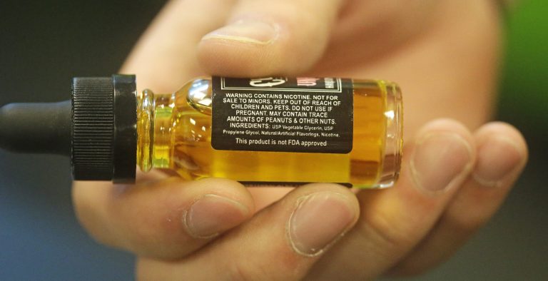 In this Aug. 14, 2014, photo, a child-proof refill bottle of liquid nicotine is shown at Salt Lake Vapors, in Salt Lake City. Poison control workers say that as the e-cigarette industry has boomed, the number of children exposed to the liquid nicotine that gives hand-held vaporizing gadgets their kick also is spiking. The American Association of Poison Control Centers reports that more than 2,700 people have called about a liquid nicotine exposure this year, up from a few hundred cases three years ago. (AP Photo/Rick Bowmer)