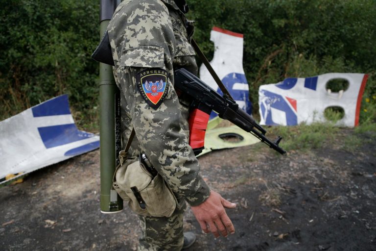 A Pro-Russian rebel stands next to pieces of the Malaysia Airlines Flight 17 plane near village of Rozsypne, eastern Ukraine, Tuesday, Sept. 9, 2014. The Dutch team investigating the downing of Malaysia Airlines Flight 17 over Eastern Ukraine says the crash was likely caused by the plane being hit by multiple 