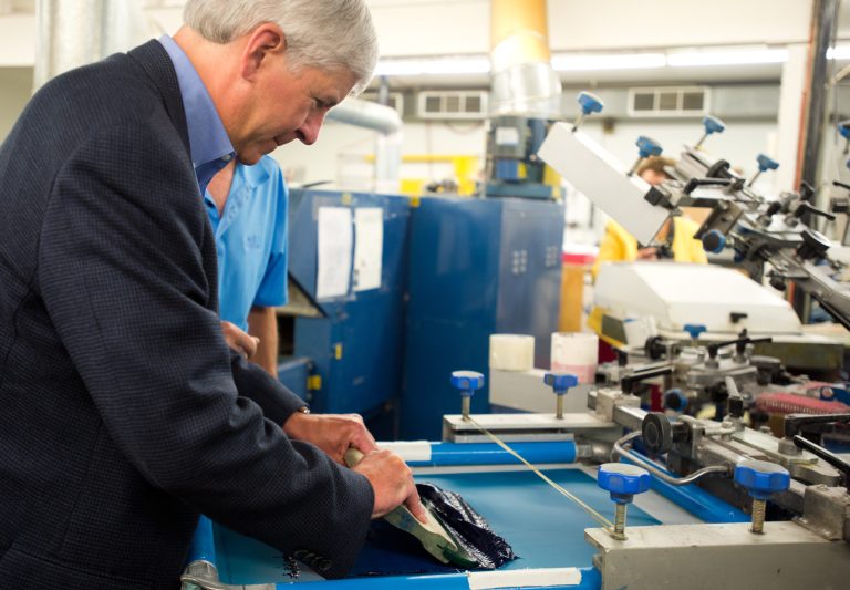 Gov. Rick Snyder prints a shirt during a tour of T.R. McTaggart Resort Apparel & Gifts in Standish, Mich. on Thursday, July 17, 2014. (AP Photo/The Bay City Times, Yfat Yossifor)