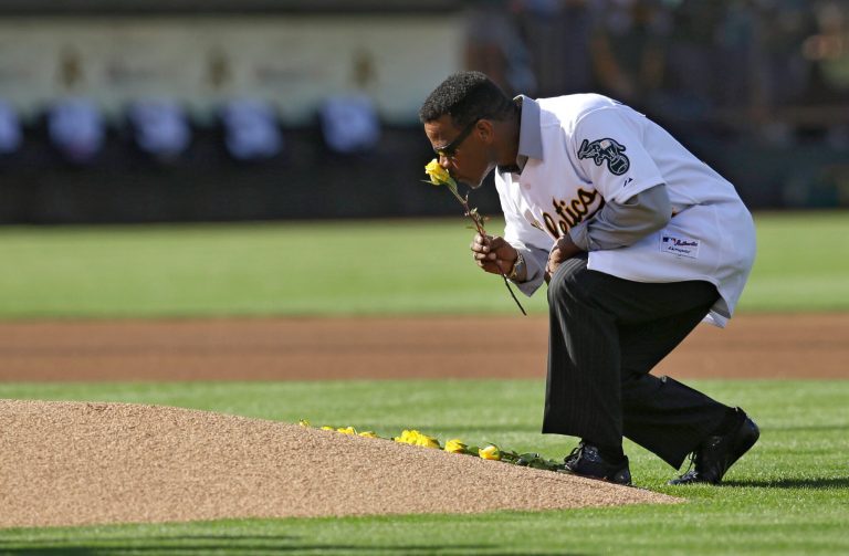 Former Oakland Athletic and Hall of Famer Rickey Henderson kisses a rose before laying it on the pitchers mound during a pre-game ceremony honoring the reunion of players from the 1989 world championship team prior to the baseball game against the Baltimore Orioles Saturday, July 19, 2014, in Oakland, Calif. (AP Photo/Ben Margot)