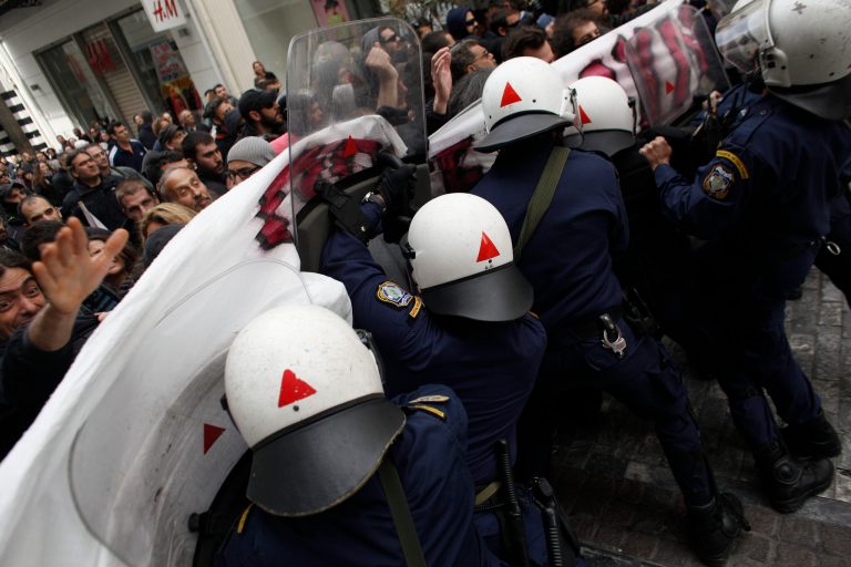 Riot policemen try to disperse demonstrators  during a protest against the opening of shops on Sundays and the extension of working hours, in Athens' Ermou shopping street, on Sunday, April 13 2014. Fitch ratings agency warned the successful bond issue didn't mean an end to Greece's financial problems. In a report Friday it said the issue showed the country's progress but doesn't mean it will be able to finance itself on its own when the bailout program ends later this year. (AP Photo/Kostas Tsironis)