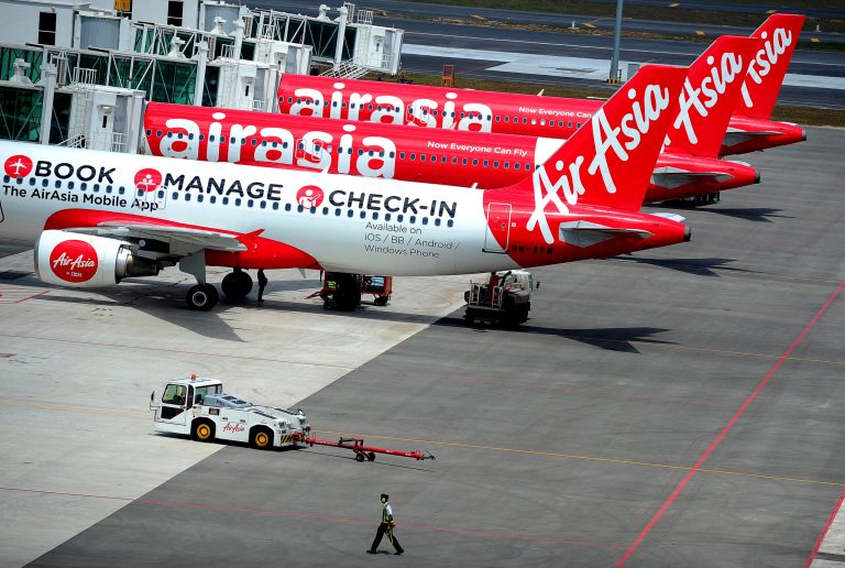 FILE - In this Friday, May 9, 2014 file photo, a ground crewman walks by a fleet of AirAsia's passenger jets on the tarmac of the new low cost terminal KLIA2 in Sepang, Malaysia, as AirAsia began its full operations from the new terminal on the day. The top Asian budget carrier said Tuesday, May 13, it will become the world's first airline to check the passports of all its passengers against Interpol's global database of 42 million stolen or lost travel documents by end of this month. (AP Photo/Joshua Paul, File)