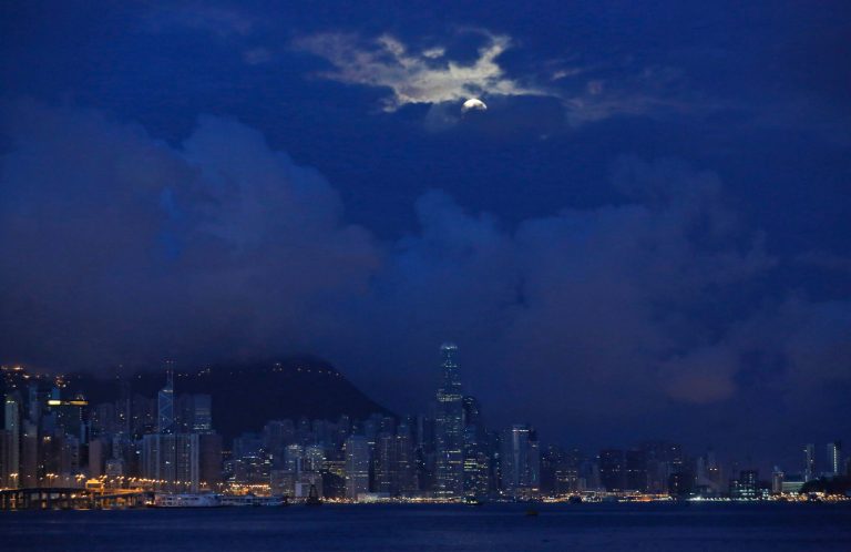 In this Aug. 11, 2014 photo, a perigee moon, also known as a super moon is half covered by cloud during the 