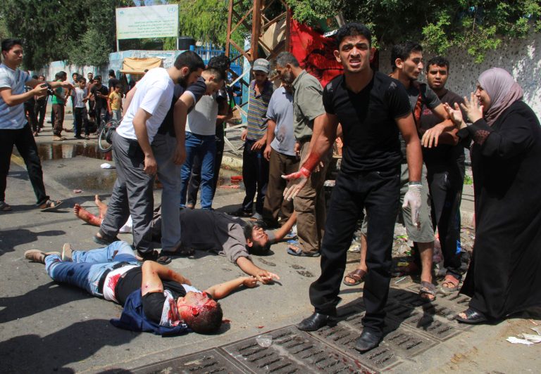 FILE - In this Aug. 3, 2014, file photo, men inspect dead and wounded Palestinians outside a U.N. run school in Rafah, in the southern Gaza Strip. The Israeli military said Wednesday, Sept. 10, it has opened criminal investigations into two high-profile cases involving Palestinian civilian casualties in this summer's Gaza war, in an apparent attempt to head off international investigations into its conduct. (AP Photo/Hatem Ali, File)