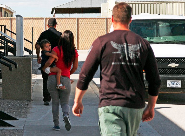 In this Sept. 10, 2014 file photo, a woman and child are escorted to a van by detention facility guards inside the Artesia Family Residential Center in Artesia, N.M. (AP Photo)Â 