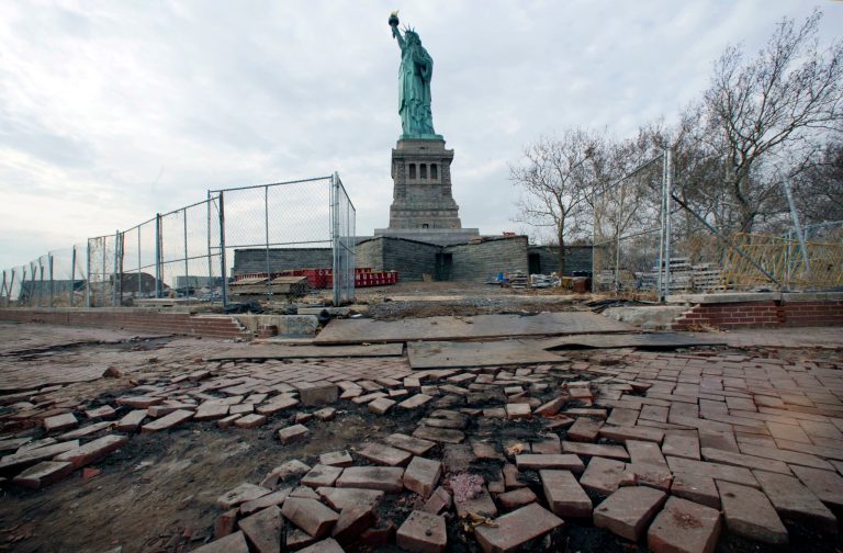 In this Nov. 30, 2012 file photo, the Statue of Liberty stands beyond parts of a brick walkway damaged in Superstorm Sandy on Liberty Island in New York. (AP Photo/Richard Drew, File)