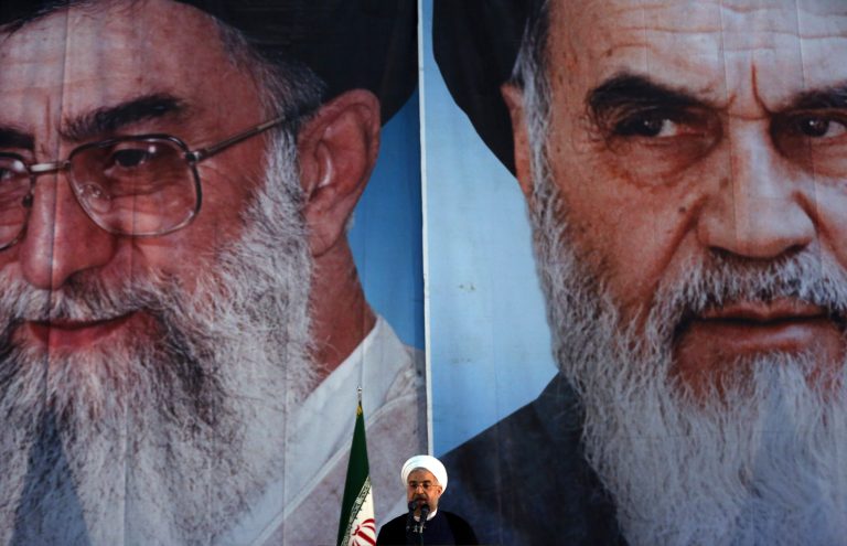 Iranian President Hassan Rouhani makes an address in front of portraits of the supreme leader Ayatollah Ali Khamenei, left, and Ayatollah Khomeini, the founder of the Islamic Republic during a ceremony marking his 25th death anniversary at his shrine just outside Tehran, Iran, Tuesday, June 3, 2014. (AP Photo/Vahid Salemi)
