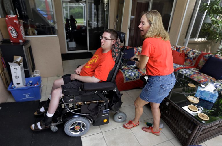  Chris Ott, right, helps her son, former Marine John Thomas Doody. J.T., who was shot while serving in Fallujah, Iraq., subsequently suffering an infection and a series of strokes that left him in a coma and relying on a ventilator to survive, Tuesday, Sept. 3, 2103, in Riverview, Fla. The Department of Veterans Affairs said Wednesday it supports expanding an enhanced caregivers benefit for grievously wounded veterans but only if Congress comes up with the billions needed to fund it. Congress created the program in 2010, giving caregivers of seriously wounded veterans a stipend, health care and at least 30 days of respite care each year. But it was limited to veterans who served after the Sept. 11 terrorist attacks. Lawmakers told the VA to study the feasibility of expansion after some veterans groups raised questions about fairness. (AP Photo/Chris O'Meara)  