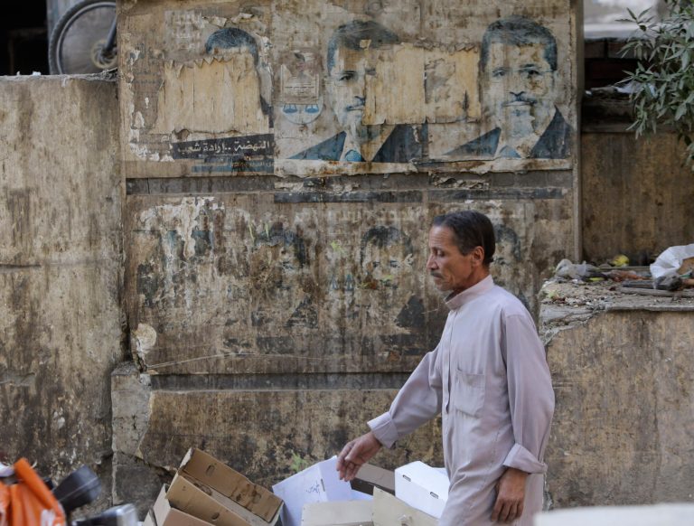 An Egyptian walks past old presidential campaign posters of ousted President Mohammed Morsi in Cairo, Egypt, Thursday, July 3, 2014. Morsi's supporters had called for mass protests Thursday to mark the anniversary, which were likely to be met with a harsh response from the security forces. (AP Photo/Amr Nabil)