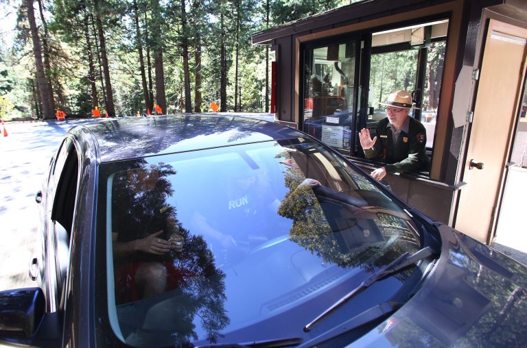 Yosemite Park Ranger Ron Morton waves goodbye to Ellie Simpson, from Chicago, at the front gate of Yosemite National Park, Calif., Thursday, Oct. 17, 2013. (AP Photo/Gary Kazanjian)