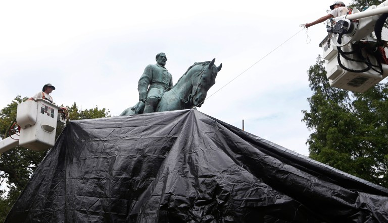 City workers drape a tarp over the statue of Confederate Gen. Robert E. Lee in Emancipation park in Charlottesville, Va., Wednesday, Aug. 23, 2017. The move intended to symbolize the city's mourning for Heather Heyer, killed while protesting a white nationalist rally earlier this month. (AP Photo/Steve Helber)