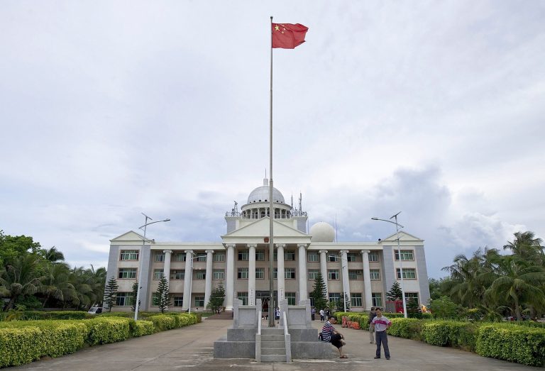 FILE - In this July 21, 2012 file photo, Chinese people chat in front of an administration office building for the Xisha, Nansha, Zhongsha islands on Yongxing Island, the government seat of Sansha City off the south China's Hainan province. China is building a school on the remote island in the South China Sea to serve the children of military personnel and others, deepening the facilities in the city it created in its campaign to claim the world's most disputed waters. (AP Photo/File) CHINA OUT