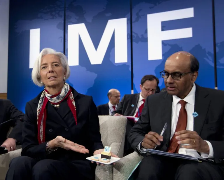 International Monetary Fund Managing Director Christine Lagarde shows photographers IMF anniversary cookies as IMFC Chairman Tharman Shanmugaratnam looks on.