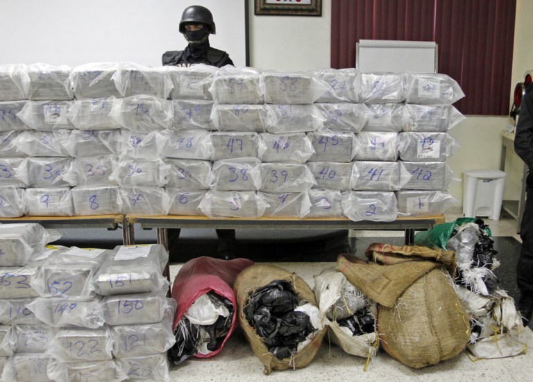 A Dominican anti-drug police officer stands behind packages of seized drugs during a news conference at the National Drug Control Agency in Santo Domingo, Dominican Republic. The Dominican Republic is now the region's biggest transit point for drugs. A U.S. military assessment projected that 6 percent of the cocaine destined for the U.S. this year will pass through the Dominican Republic alone. (AP Photo/Manuel Diaz)