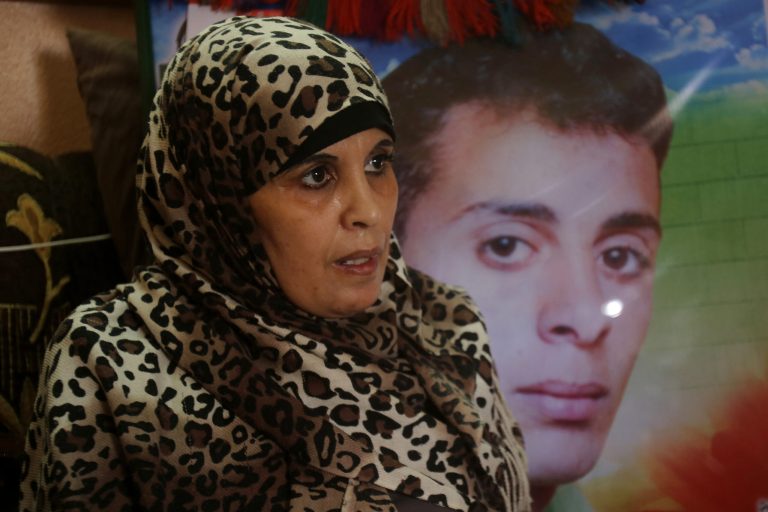 In this June 3, 2014 photo, Rawda Zanoun, 48, speaks during an interview with The Associated Press in front of a portrait of her son, Alaa Eldin, who was killed in a 2007 fight between Hamas and Fatah days before the Hamas take over in Gaza City. Foes Hamas and Fatah managed to set aside some of their differences to form a Palestinian unity government, but the hardest part of reconciliation may still lie ahead. (AP Photo/Hatem Moussa)