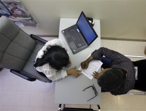 Clinical applications counselor Rachael Richardson, left, works with Louis Peters at the Henry J. Austin Health Center, in Trenton, N.J., as he and others fill out papers to sign up for new plans through an Obamacare health insurance exchange. (AP Photo/Mel Evans)