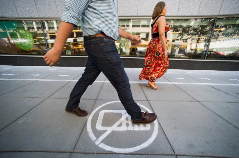 As part of their Mind Over Masses television show, National Geographic divided a one block-long sidewalk into two sections; one for cell phone users and the other for those not using a cell phone in downtown Washington, Thursday, July 17, 2014. The walkway warnings were put there by the brains behind a National Geographic television show as part of a behavioral science experiment. (AP Photo/Cliff Owen)