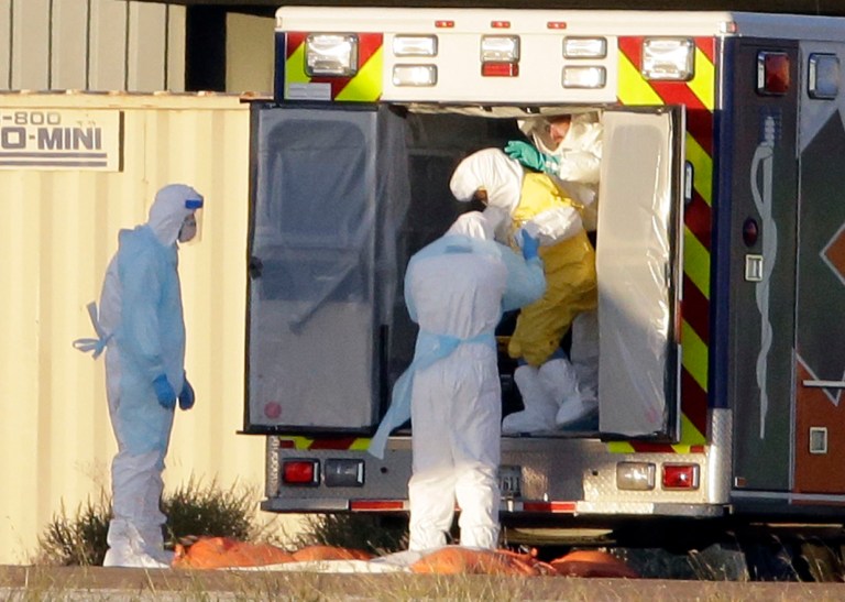 Medical staff in protective gear escort Nina Pham, exiting the ambulance, to a nearby aircraft at Love Field, Thursday, Oct. 16, 2014, in Dallas. Pham, a nurse at Texas Health Presbyterian Hospital Dallas, was diagnosed with the Ebola virus after caring for Thomas Eric Duncan who died of the same virus. (AP Photo/Tony Gutierrez)