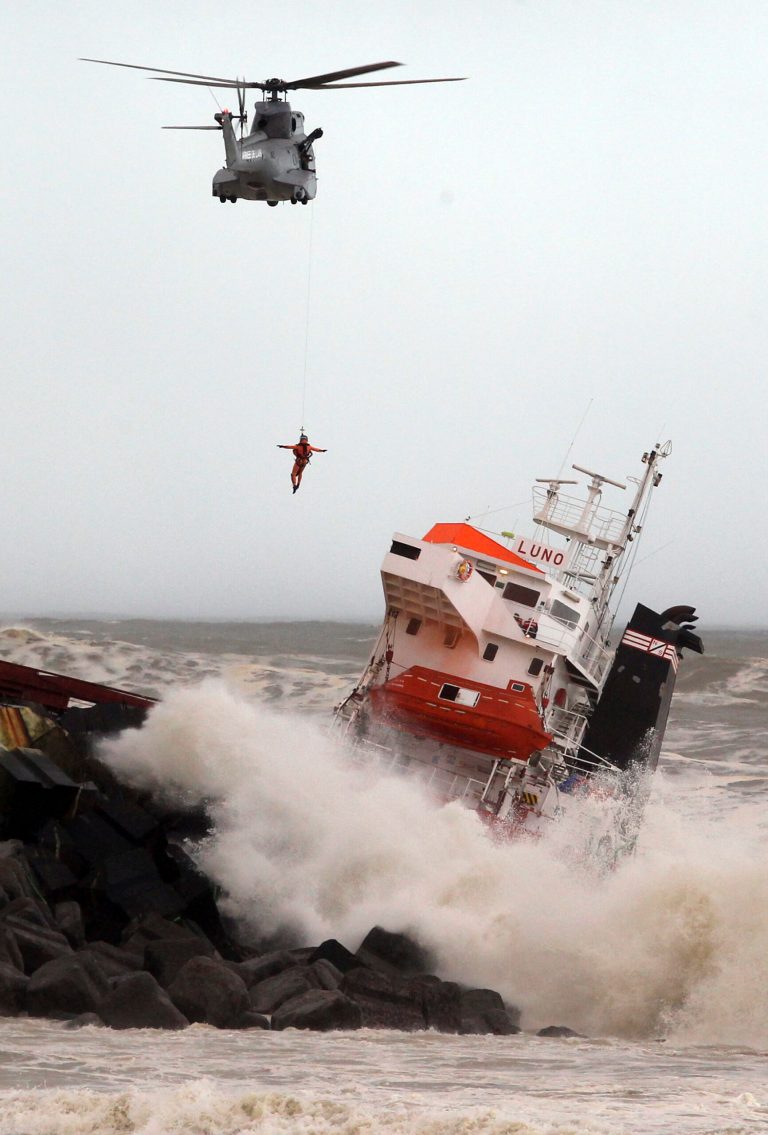 A helicopter lowers a rescue worker toward a Spanish cargo ship that slammed into a jetty in choppy Atlantic Ocean waters off Anglet, southwestern France, Wednesday Feb. 5, 2014.  The ship had been heading to a nearby port to load up with cargo when its engine failed and the rough waves carried it into the jetty. (AP Photo/Bob Edme)