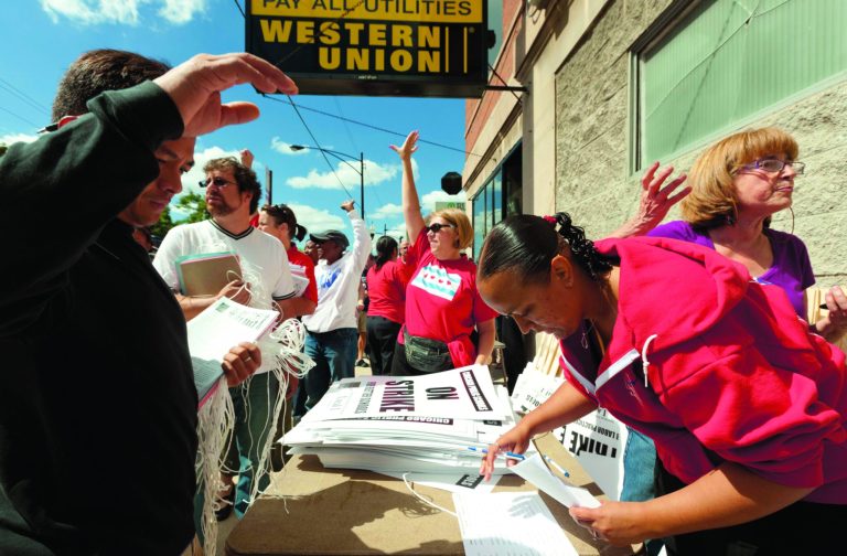 Teachers respond enthusiastically to passing drivers honking their horns in support as they distribute strike signage at the Chicago Teachers Union strike headquarters on Saturday, Sept. 8, 2012 in Chicago. The union has vowed to strike on Monday, Sept. 10, 2012, should it fail to reach an agreement over teachers' contracts with Chicago Public Schools by that date. (AP Photo/Sitthixay Ditthavong)