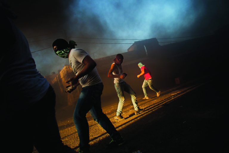FILE - In this Tuesday, Sept. 18, 2012 file photo, masked Palestinians throw stones towards Israeli security forces, not pictured, during clashes that erupted after a demonstration against an anti-Islam film called 