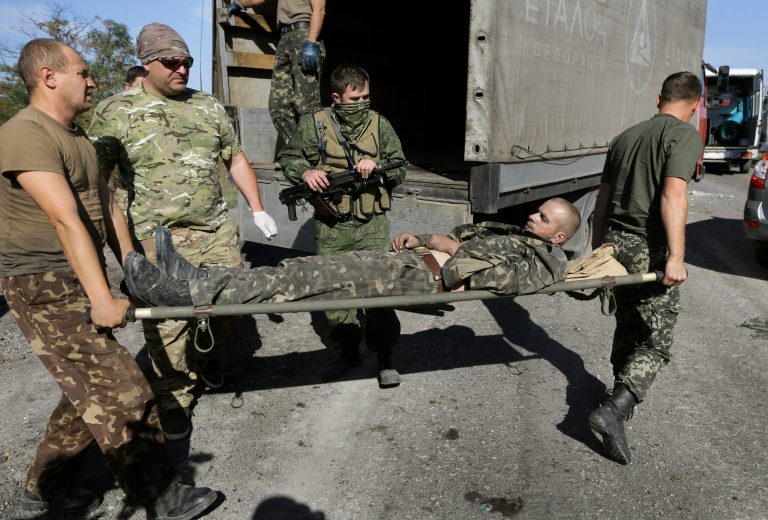 Ukrainian army personnel carry an Ukrainian government soldier injured by tank fire to an ambulance in the rebel-held town of Starobesheve, eastern Ukraine, Saturday, Aug. 30, 2014.  Half an hour later the soldier died.  Ukrainian government forces have succumbed to a sequence of military failures and seen their holdings in the conflict-ridden east shrink in recent days as Russian-backed rebels continue their fast-paced offensive. (AP Photo/Sergei Grits)