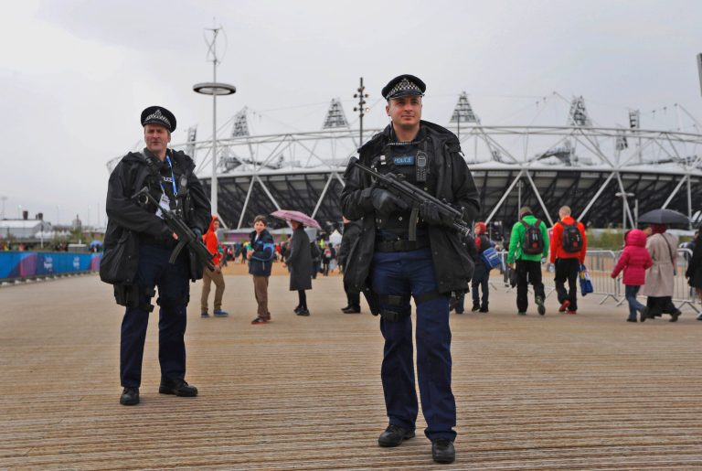   FILE This , Saturday, May 5, 2012 file photo shows armed British police officers posing for photographers whilst patrolling during the British Universities and Colleges Sport Athletics Championship (BUCS) outside the Olympic Stadium in the Olympic Park in London. Britain is pouring more money into plans to control the massive crowds expected in London during the Olympics, with the government acknowledging Wednesday June 13, 2012 that it had vastly underestimated the number of people likely to take part in the heady atmosphere of the city. (AP Photo/Matt Dunham)  