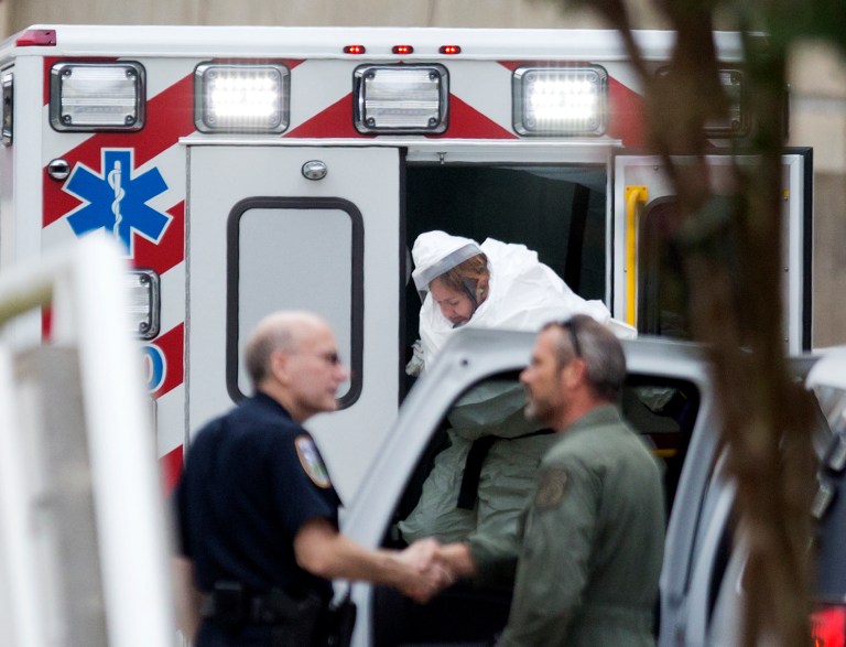 A person wearing a haz-mat suit steps out of an ambulance as an ebola patient arrives for treatment, Tuesday, Sept. 9, 2014, in Atlanta. The fourth American aid worker sickened with the Ebola virus arrived Tuesday morning for treatment at Emory University Hospital, where two others have been successfully treated. (AP Photo/David Goldman)